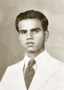 Black and white portrait of a young man wearing a suit and tie with a neutral expression.