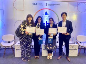 Four people stand indoors holding certificates, posing for a photo at the Raisina Dialogue event organized by ORF and the Ministry of External Affairs, India.