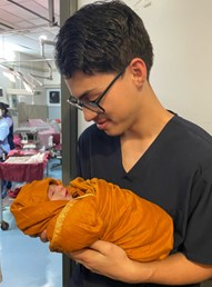 Person in scrubs holding newborn